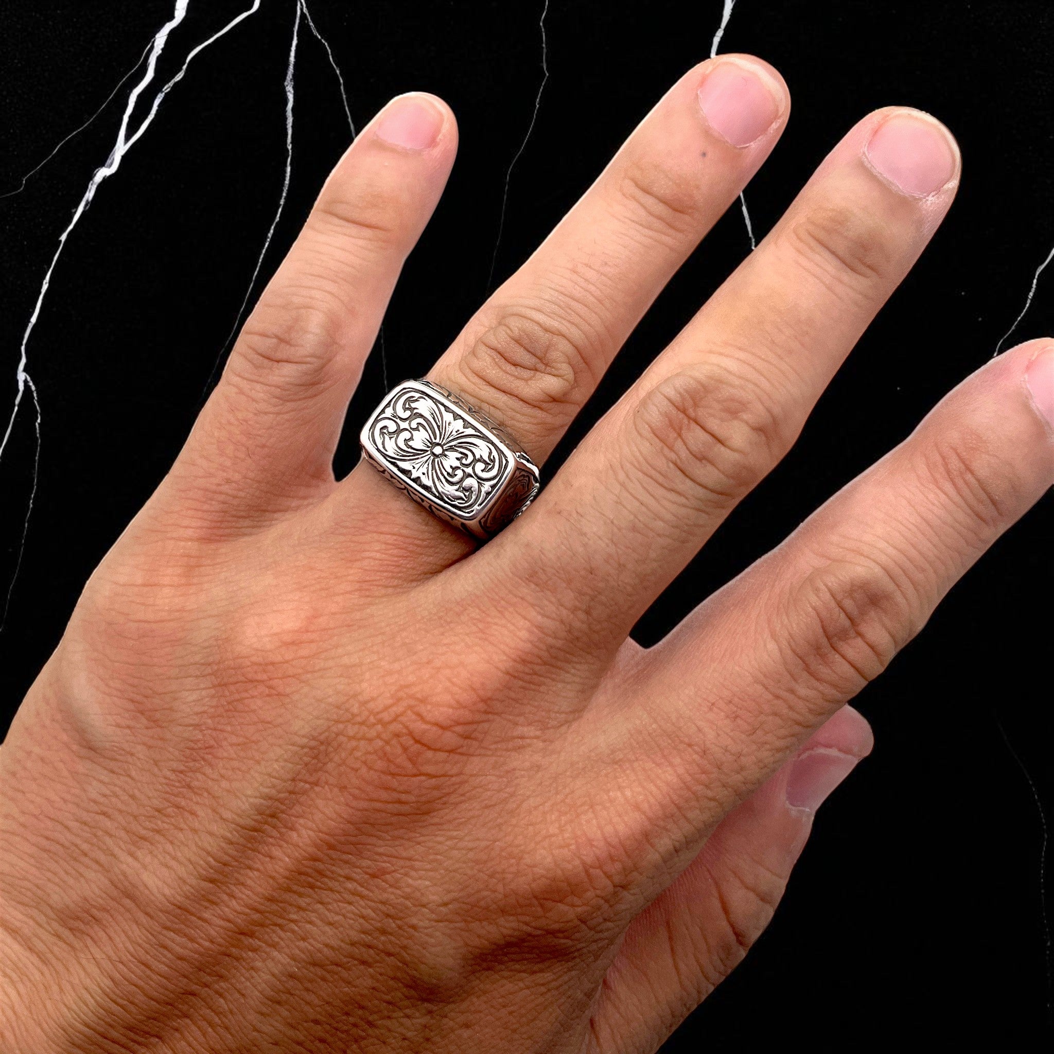 シルバーリング emblem の着用写真。四角いフェイスにシンメトリーな植物模様をエングレービングで彫金したデザインが特徴のエングレービングリング。