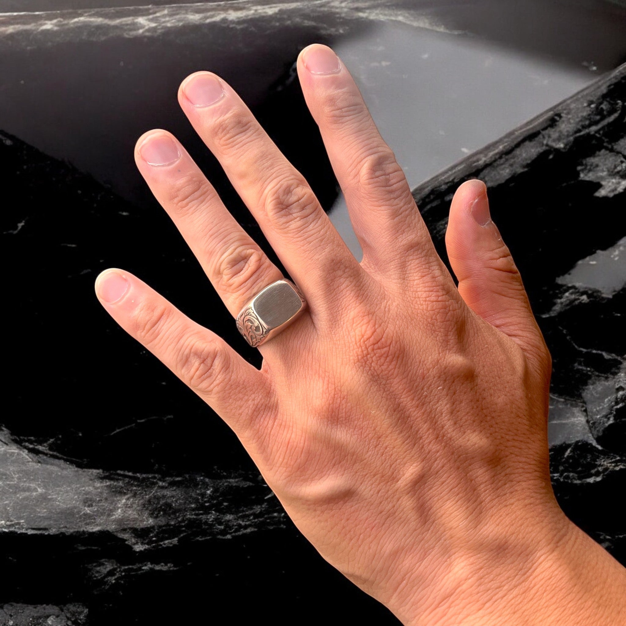 シルバーリング ivy の着用写真。シグネットリングの側面に植物模様を彫金し、正面は無地の鏡面仕上げで、手元を上から映したイメージ。