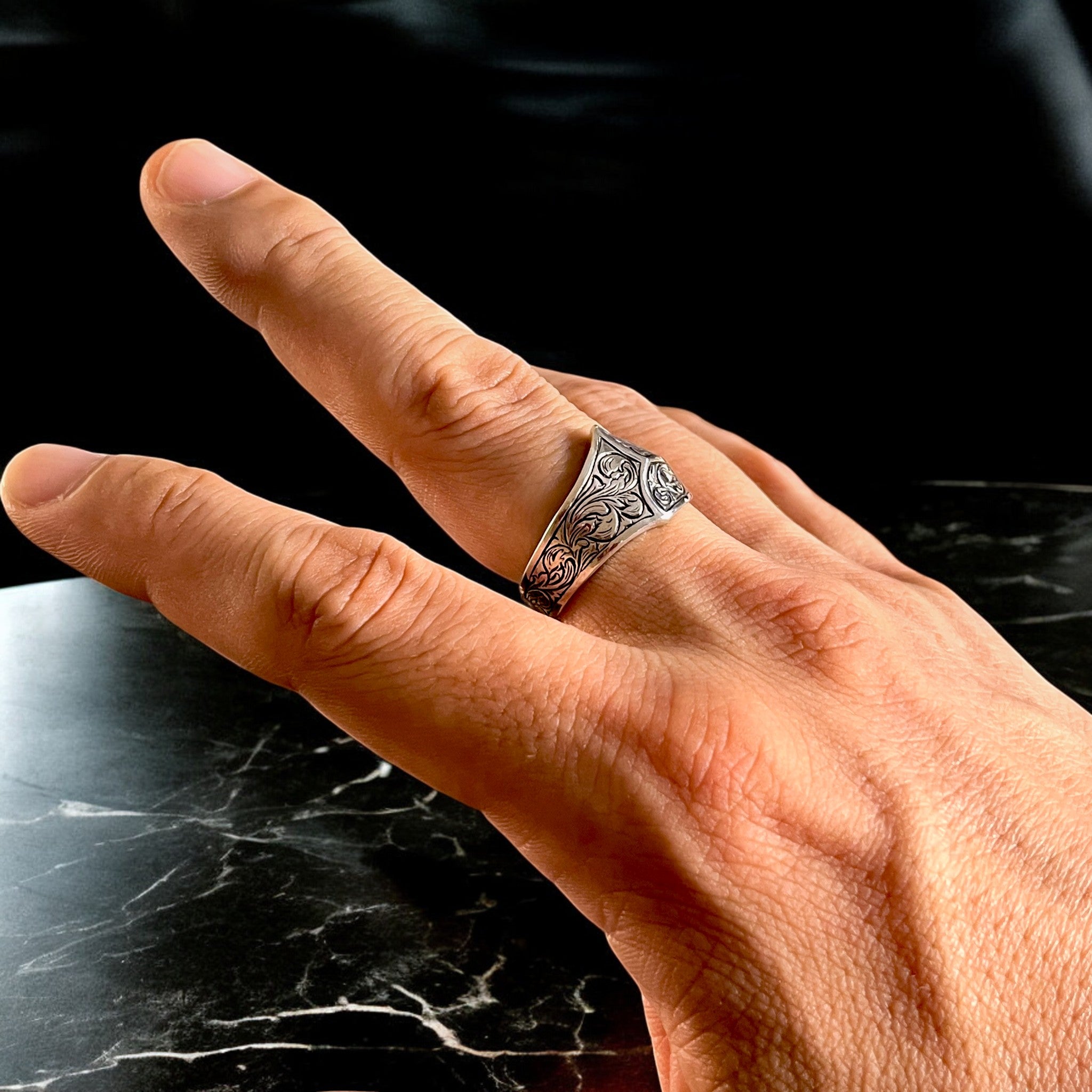 シルバーリング icon の着用写真。シグネットリングのアーム全体に植物模様を彫金し、横から見た角度で立体的な装飾の美しさを映したイメージ。