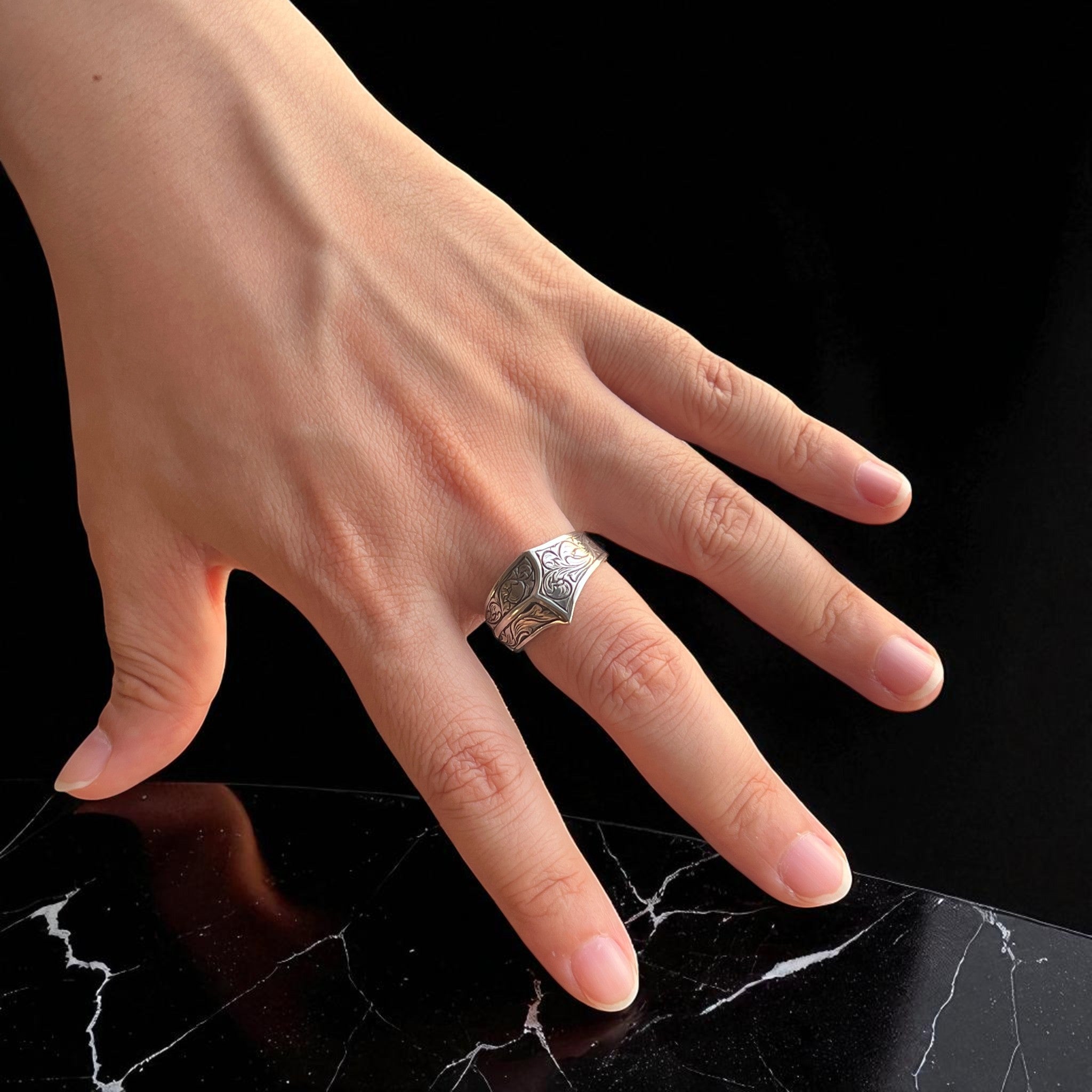 シルバーリング icon の着用写真。女性の手にシグネットリングを着け、側面から天面にかけて彫金された植物模様のデザインを映したイメージ。