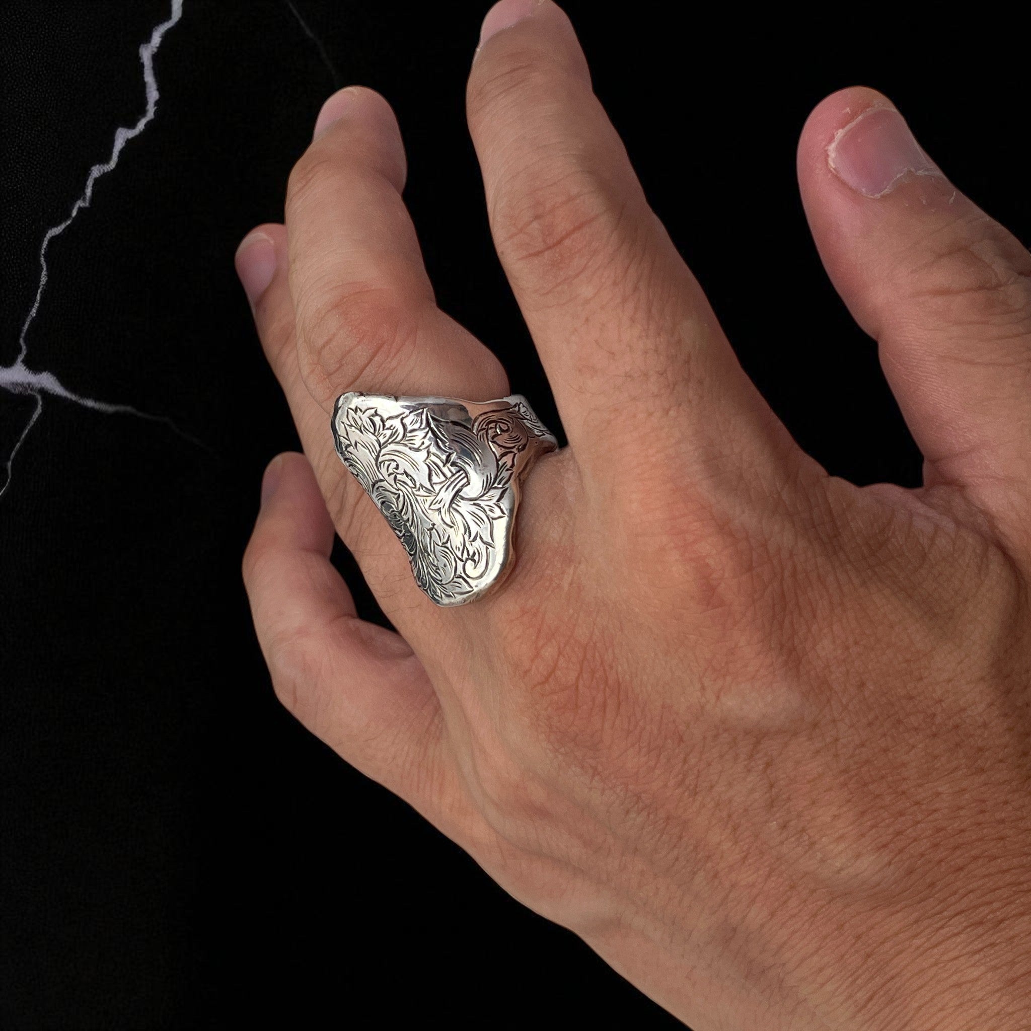 シルバーリング mythⅡ の着用写真。斜め後方から映した角度で、植物模様をエングレービングした繊細な彫金とリングの厚みや曲線的なフォルムを表現したデザイン。